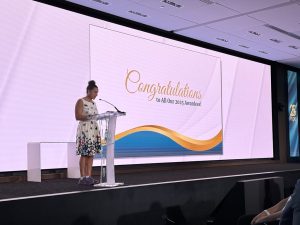 A woman stands at a podium on a stage