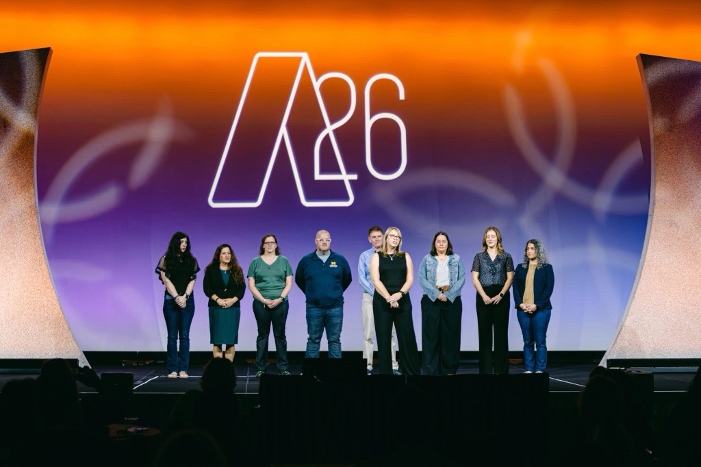 Nine people stand on a stage at a conference